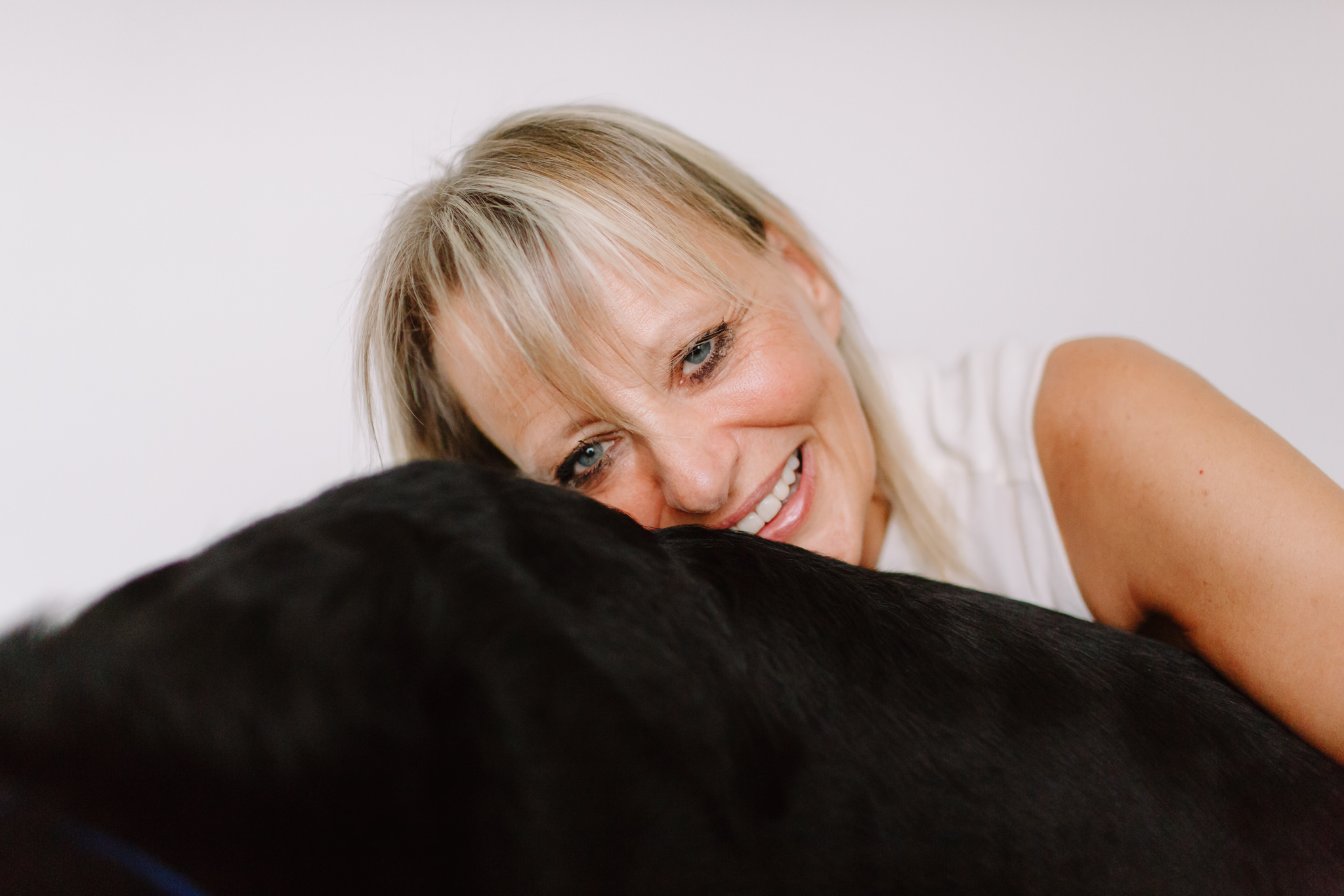 Woman leans on black dog and smiles
