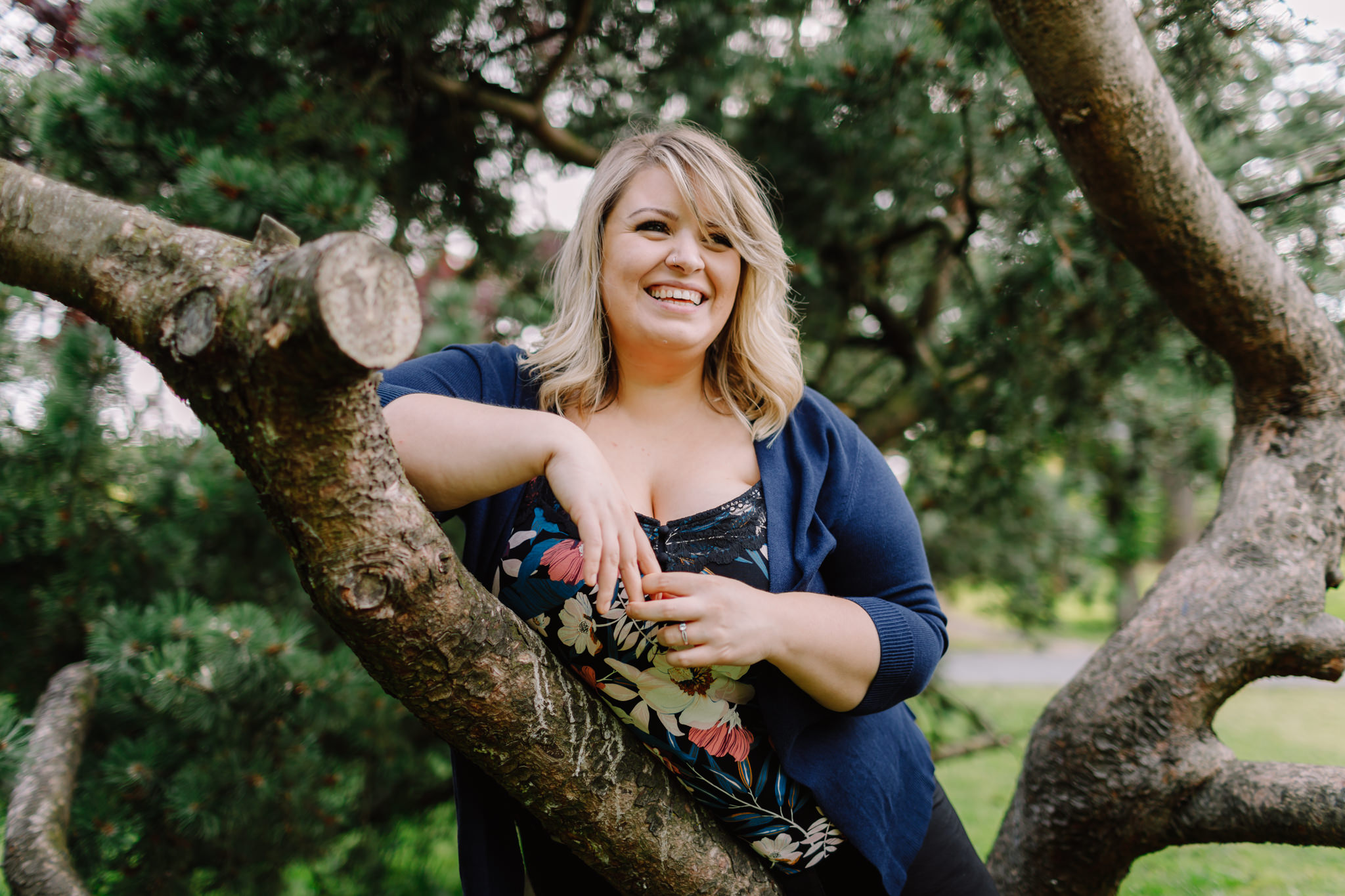 Woman leans on tree branch smiling