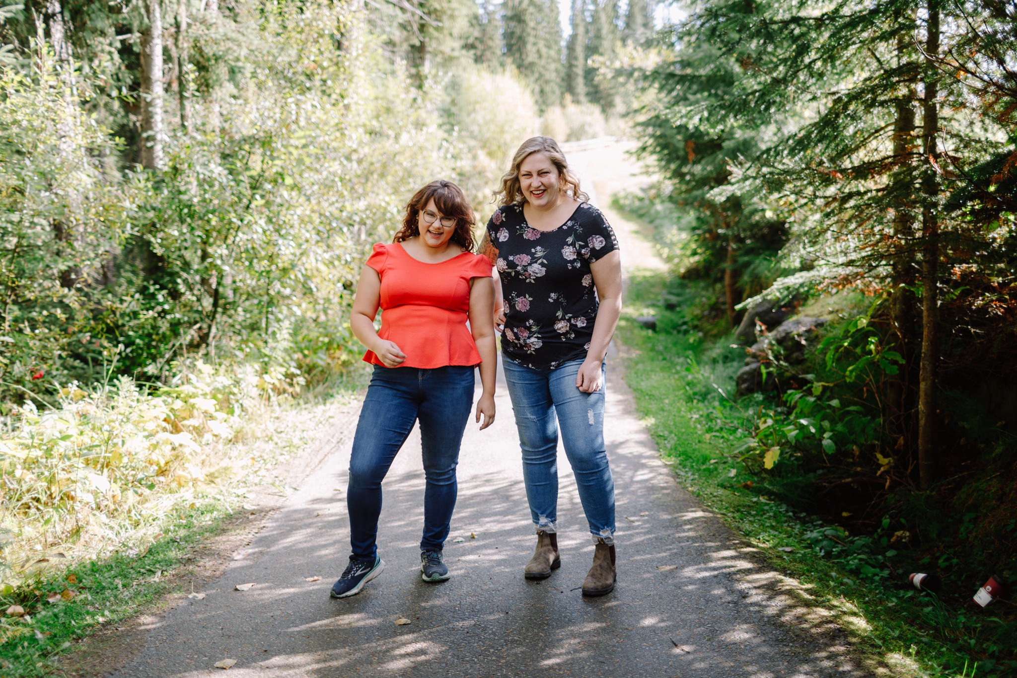 Two women stand together smiling in country lane