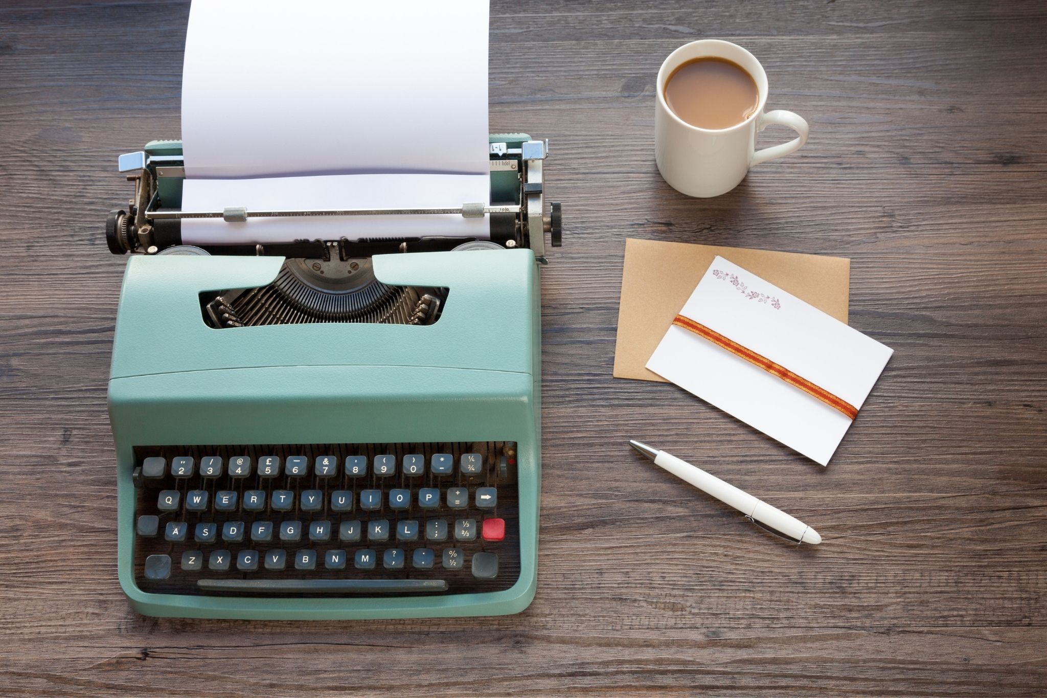 green typewriter on desk with coffee and notebook