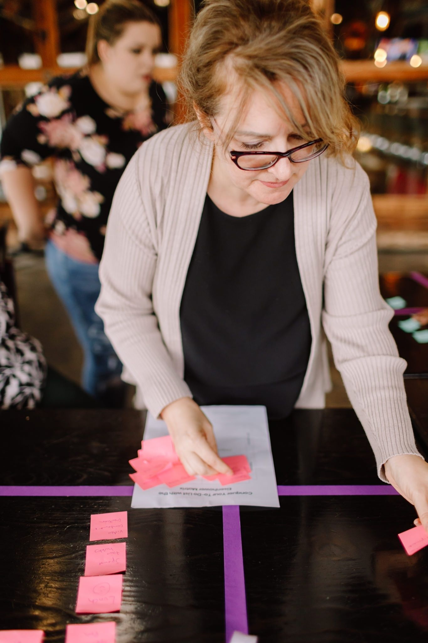 Woman at a workshop event sticks post it notes to a grid on a table