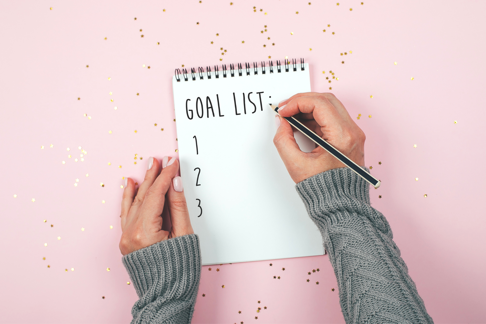 Woman writes a goal list on a pink background with glitter