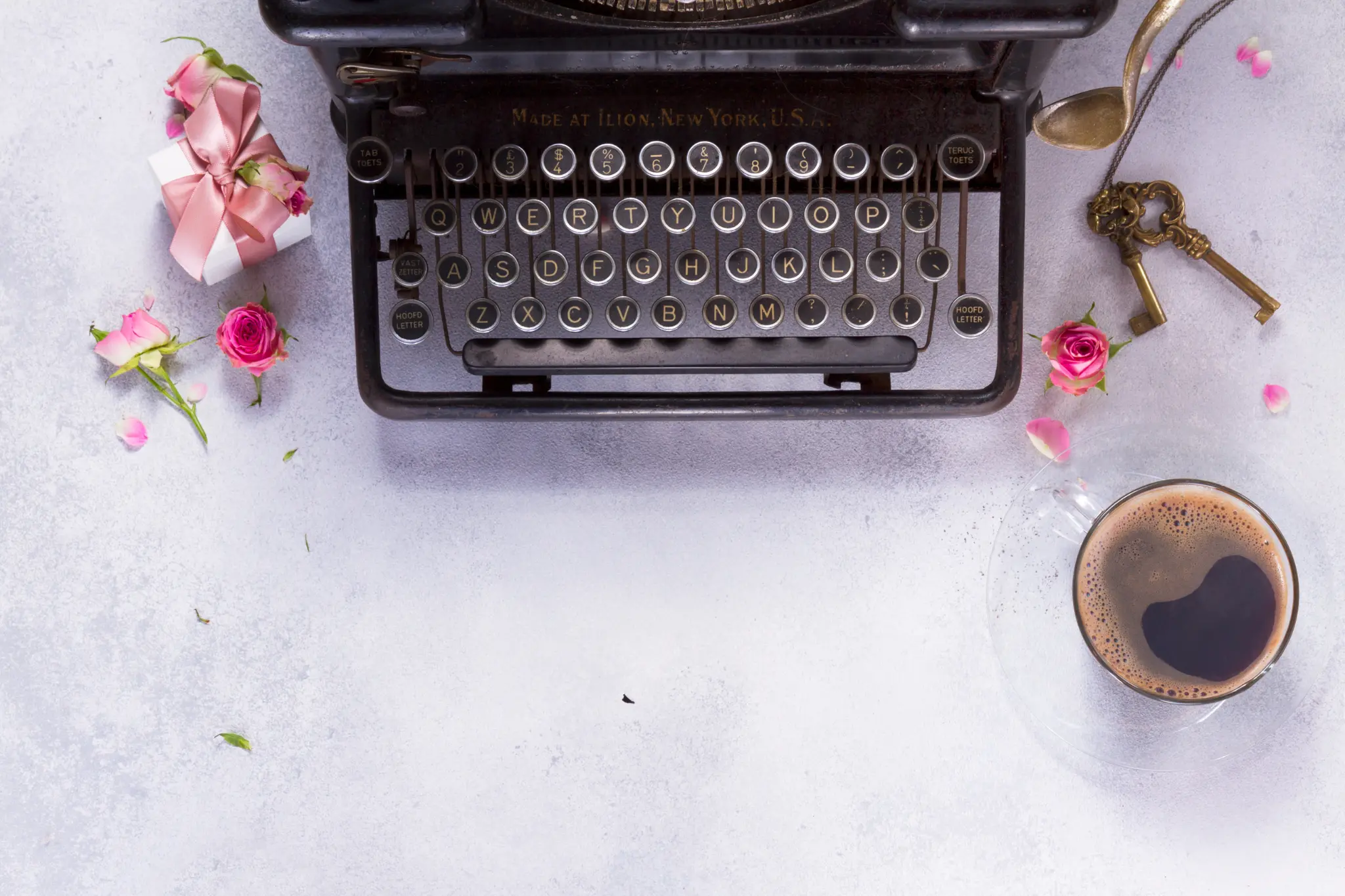 Flat lay photograph of a vintage typewriter and a cup of coffee with flowers. A great way to find the right copywriter for your creative business.